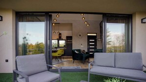 Een moderne woonkamer met grijze banken, een salontafel en een potplant.