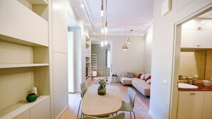 A modern kitchen with a dining area, a sofa, and a bathroom visible through an open door. - The Garden of the Muse (Roma)