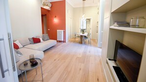 A modern living room with a sofa, a dining table, and a fireplace. - The Garden of the Muse (Roma)