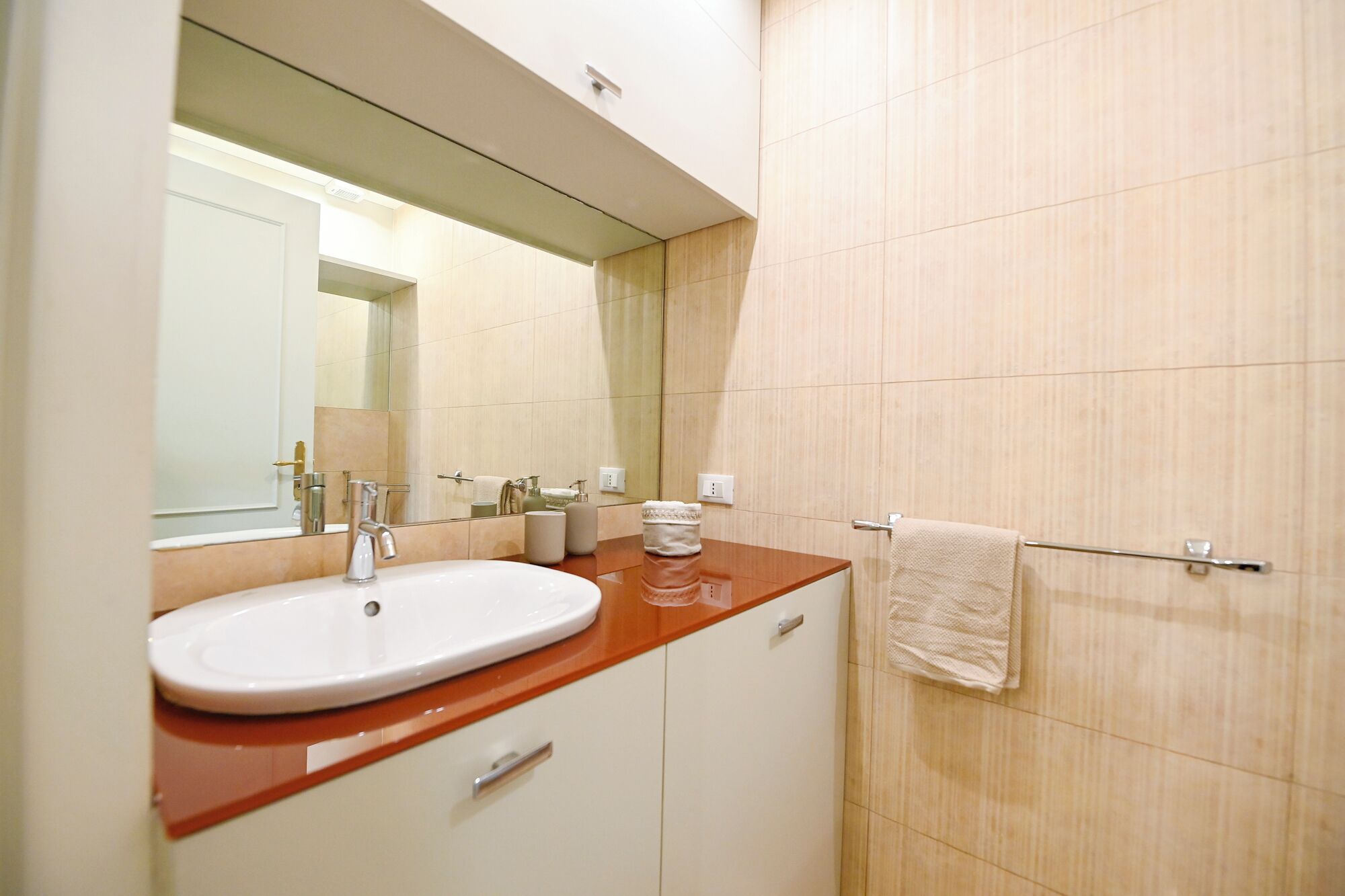 A bathroom with a white sink, a mirror, and a towel rack.