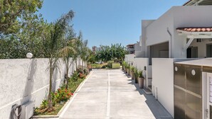 A clean, modern building with a straight pathway lined with potted plants and a clear sky. - Aloe,pool,near beach & amenities no car needed (Adelianos Kampos)