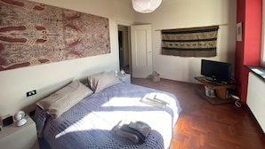 A bedroom with a bed, a hanging light fixture, a television, and a wall tapestry. - Villa in the Green in the hills in Lavagna - 3 Bedrooms, Garden and Private Parking (Lavagna)