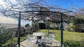 A patio area with a pergola, a round table, and white chairs. - Villa in the Green in the hills in Lavagna - 3 Bedrooms, Garden and Private Parking (Lavagna)