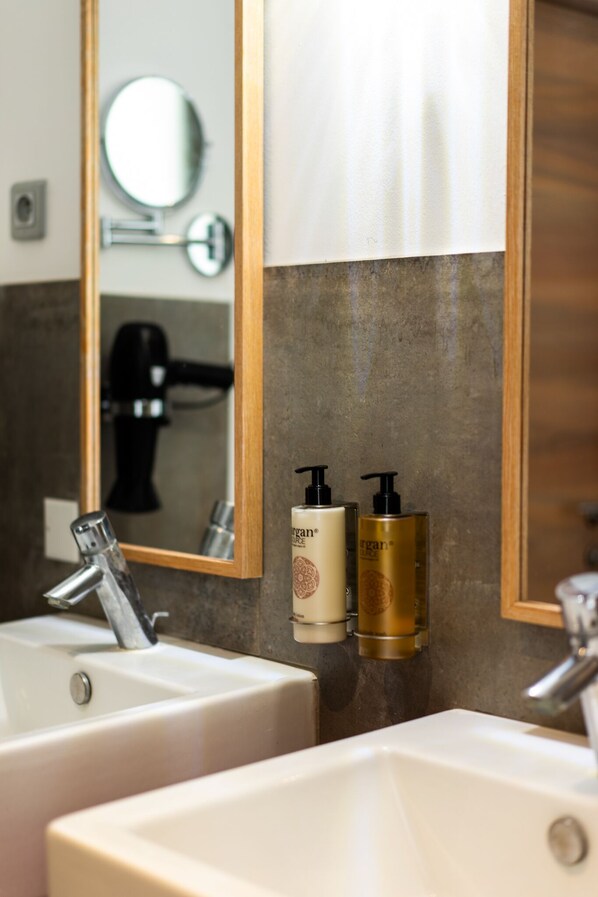 A bathroom with two sinks, a mirror, and two bottles of lotion.