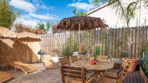 An outdoor patio with wooden furniture, a barbecue grill, and a thatched umbrella. - Private Garden La Cabane Bambou, Mandara Beach (Antibes)