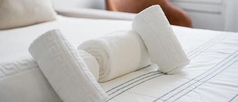 A neatly made bed with rolled white towels and a striped bedspread.