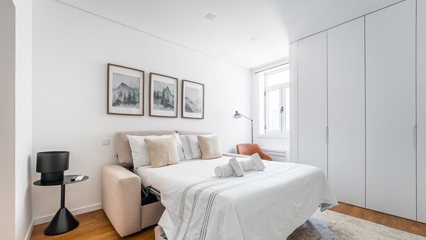 A bedroom with a bed, bedside tables, a wardrobe, and framed pictures on the wall. - GuestReady - Inviting Hideaway in Matosinhos (Matosinhos)