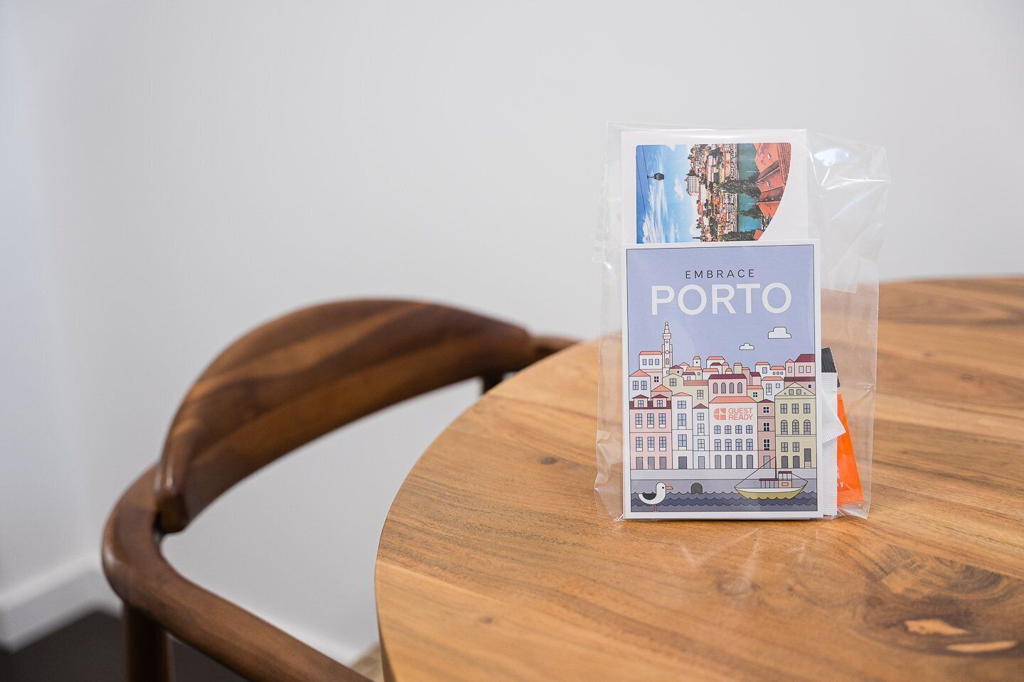 Un artículo empaquetado con la etiqueta “EMBRACE PORTO”, con una ilustración de un paisaje urbano, sobre una mesa de madera.