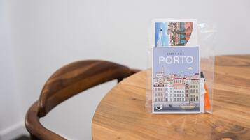 Un artículo empaquetado con la etiqueta “EMBRACE PORTO”, con una ilustración de un paisaje urbano, sobre una mesa de madera.