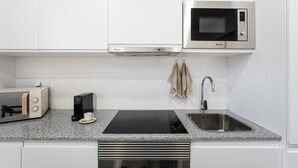 A modern kitchen with white cabinets, a built-in microwave, a coffee maker, and a sink. - GuestReady - Inviting Hideaway in Matosinhos (Matosinhos)