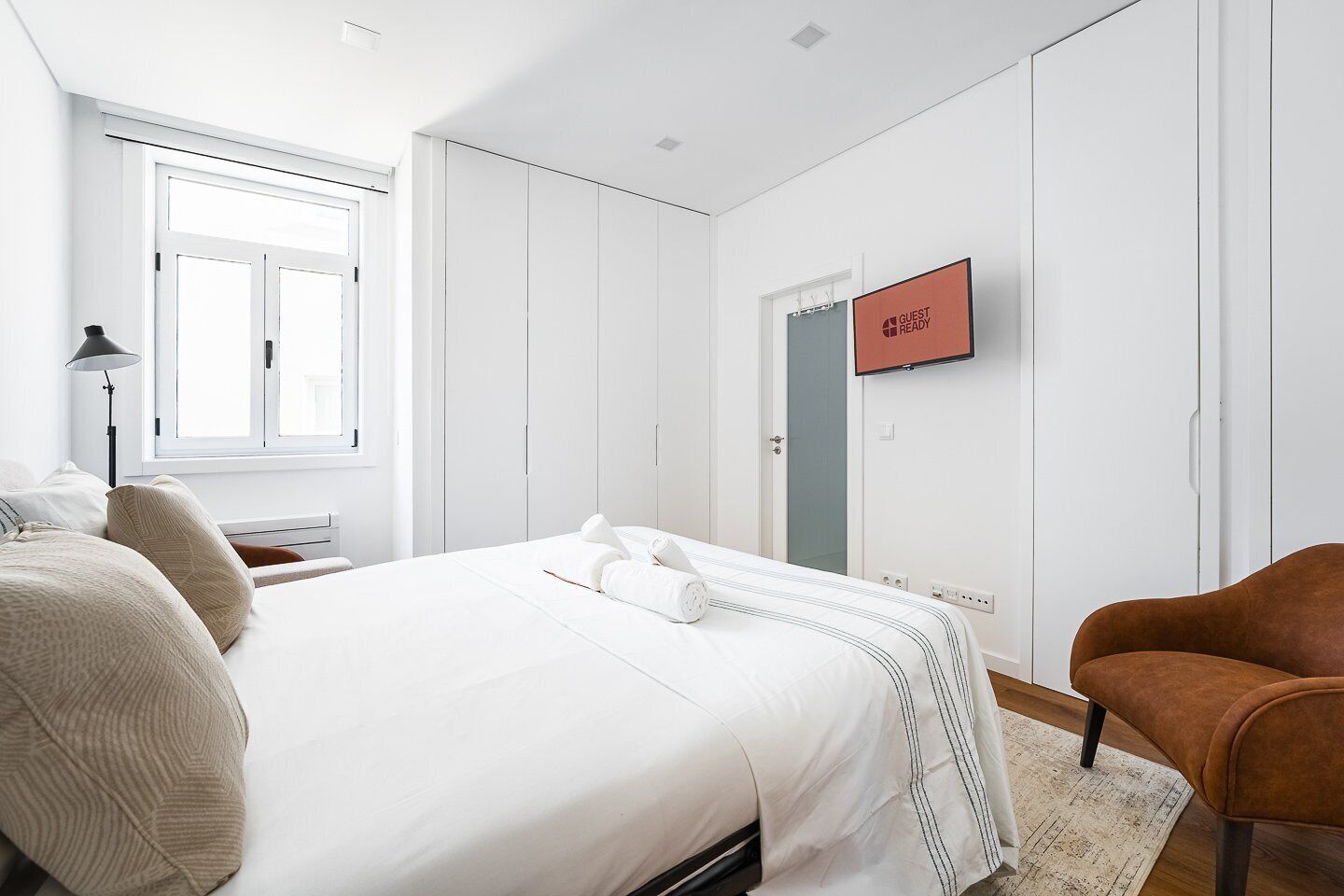 Una camera d'albergo moderna con un letto grande, una scrivania, una sedia e un armadio.