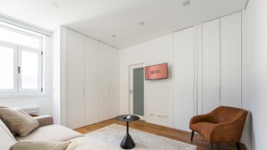 A modern, minimalist room with a beige sofa, a brown armchair, a small black table, and a 'GUEST READY' sign on the wall. - GuestReady - Inviting Hideaway in Matosinhos (Matosinhos)