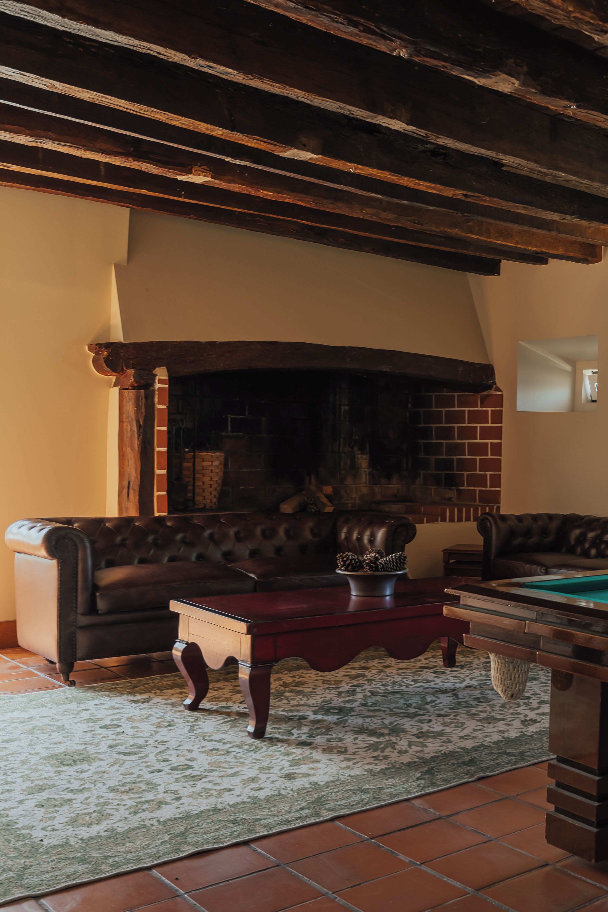 Una sala de estar acogedora con chimenea, sofás de cuero y mesa de billar.