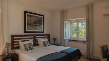 A double bed with a wooden headboard, two bedside tables with lamps, a window with curtains, and a chair.