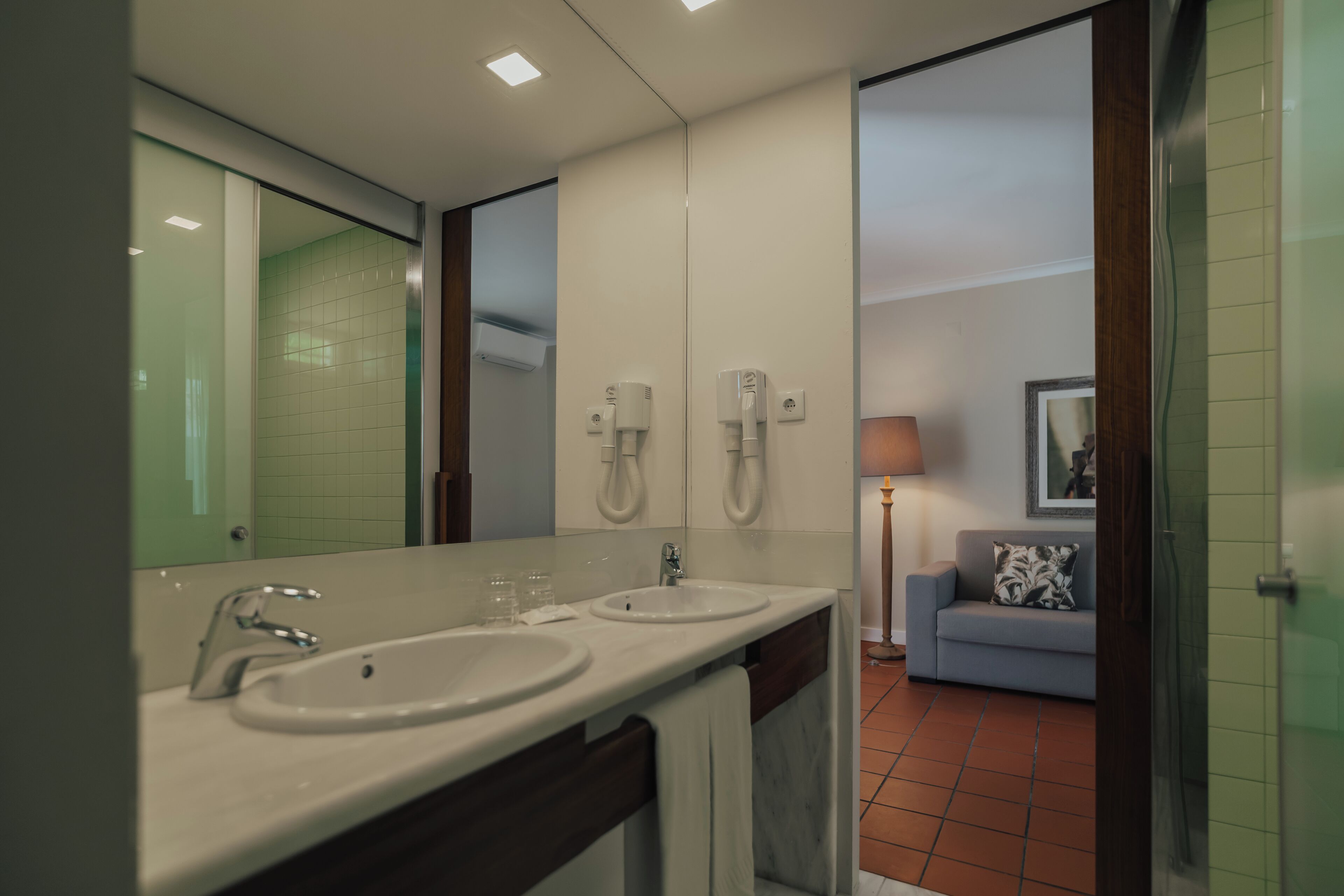 A bathroom with two sinks, a mirror, and a towel rack.
