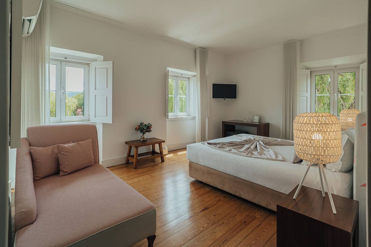 Une chambre à coucher avec un lit, un canapé, une télévision et une fenêtre avec des rideaux.