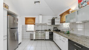 A modern kitchen with a stainless steel refrigerator, built-in oven, and granite countertop.