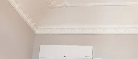 Un equipo de aire acondicionado blanco montado en una pared, con un techo decorativo.