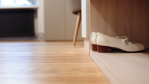Um par de sapatos brancos sobre um chão de madeira perto de um banco de madeira.