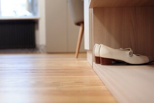 Un par de zapatos blancos sobre un suelo de madera cerca de un banco de madera.