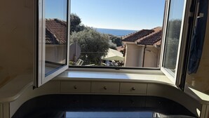 A bay window with a view of a residential area, including houses with red-tiled roofs and greenery. - The Piano Apartment (Imperia)