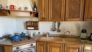 A kitchen with wooden cabinets, a stove, and a sink. - The Piano Apartment (Imperia)