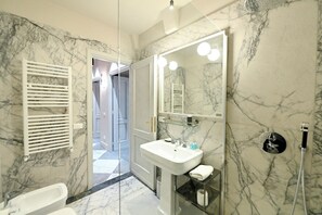 A modern bathroom with a marble floor, a white sink, a large mirror, and a glass shower enclosure. - Domus Notabilis 35 (Roma)