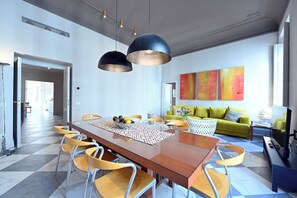 A modern dining area with a wooden table and yellow chairs, a green sofa with patterned cushions, and abstract wall art. - Domus Notabilis 35 (Roma)