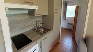A compact kitchen with a built-in stove, a sink, and a small countertop. - Apartment with balcony near beach (Six-Fours-les-Plages)