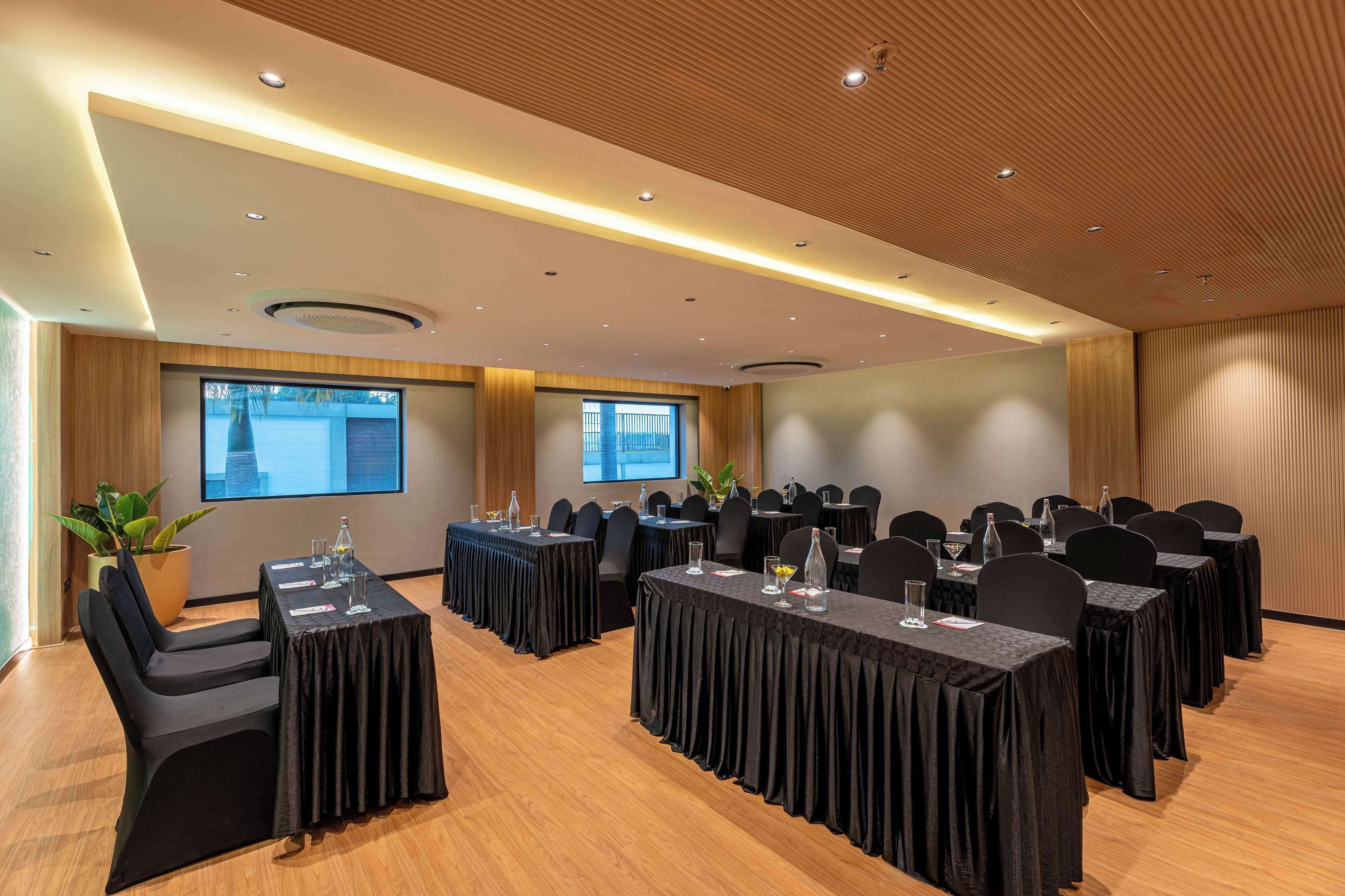 A conference room with multiple tables, chairs, and a large screen.
