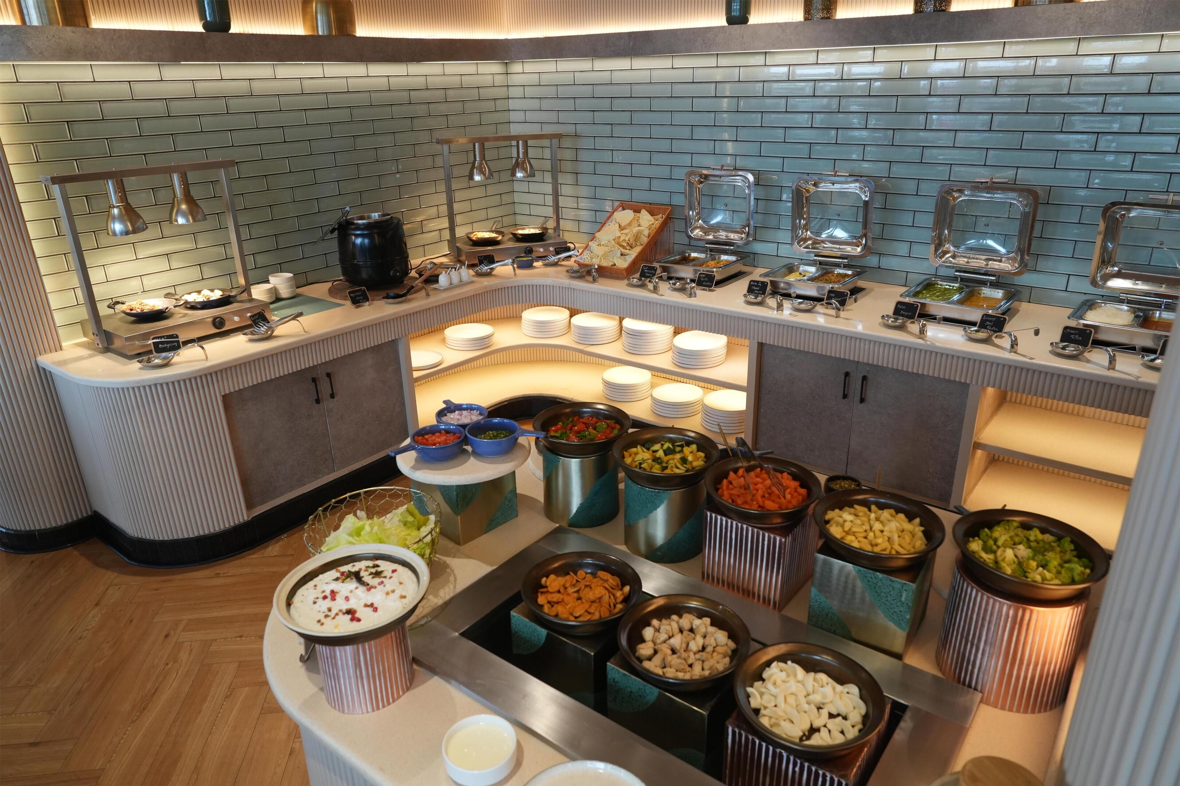 Zona de buffet con distintas opciones de comida, incluyendo una barra de ensaladas y una estación de comida caliente.