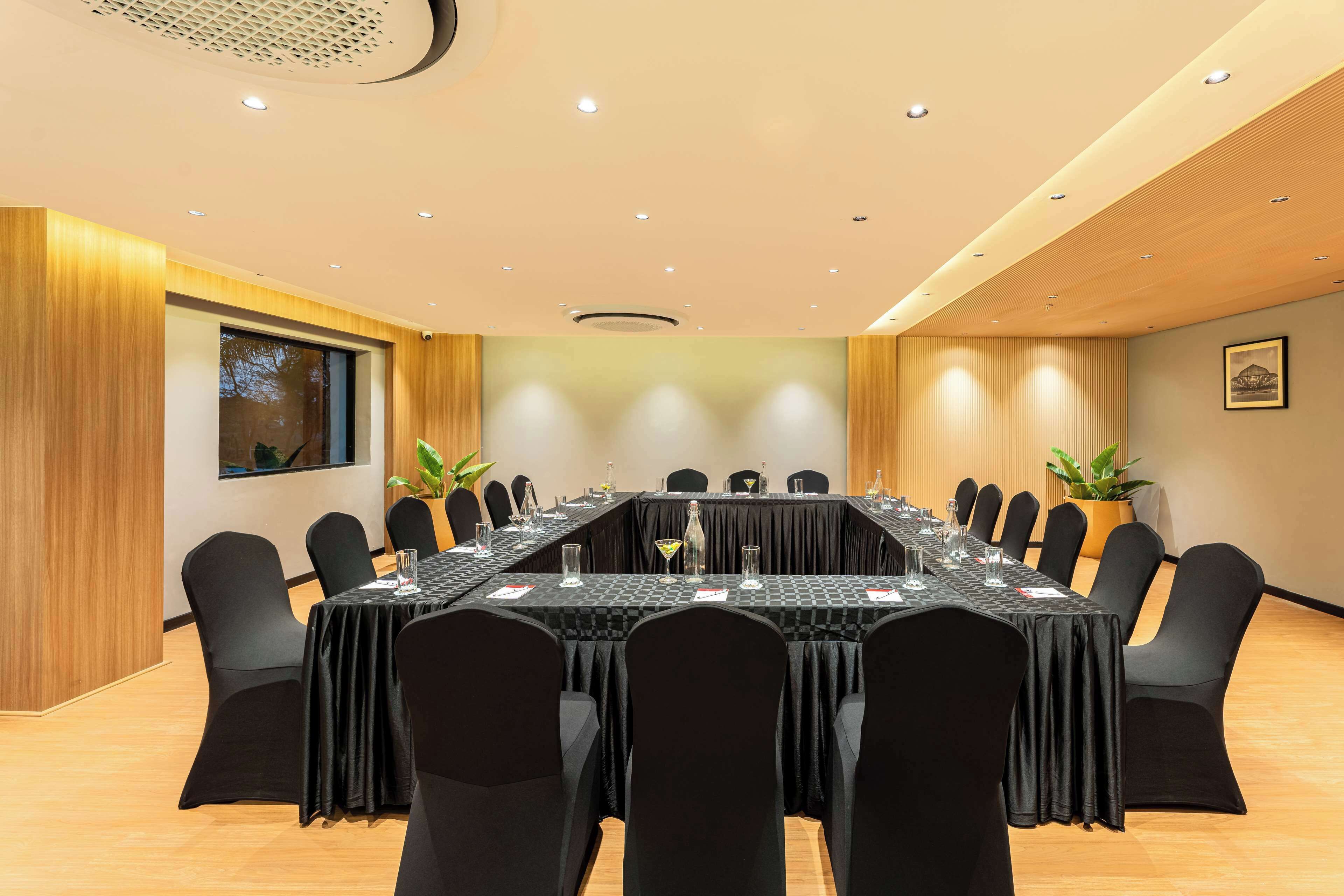 Une salle de conférence avec une longue table, des chaises noires et un plafond en bois.