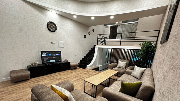 A modern living room with a flat-screen TV, a wooden coffee table, and a sofa set. - Duplex two bedroom apartment (Tbilisi)