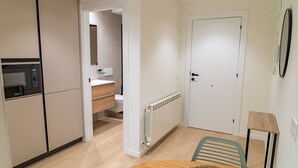 Una cocina moderna con microondas integrado, una mesa de comedor de madera y un camino a un baño contiguo.