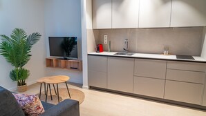 Una cocina moderna con un lavaplatos integrado, un televisor de pantalla plana y una pequeña zona de comedor con una mesa y sillas.