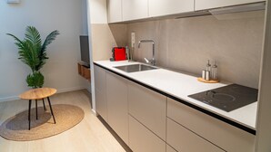 Una cocina moderna con un lavaplatos integrado, una estufa y una pequeña mesa de madera con un tapete tejido.