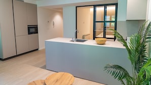 Uma cozinha moderna com ilha central, eletrodomésticos embutidos e uma porta de vidro deslizante que dá para uma varanda.