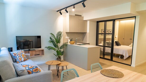 Uma sala de estar moderna com sofá, TV, mesa de jantar e cozinha.