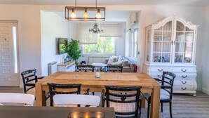 A dining area with a wooden table, black chairs, a chandelier, and a white cabinet with glass doors. - Beautiful Rural House in Nava (Nava)
