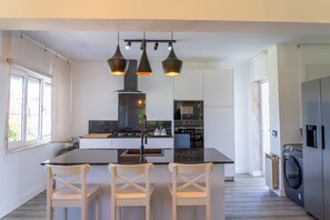 A modern kitchen with a central island, three pendant lights, and a built-in oven. - Beautiful Rural House in Nava (Nava)