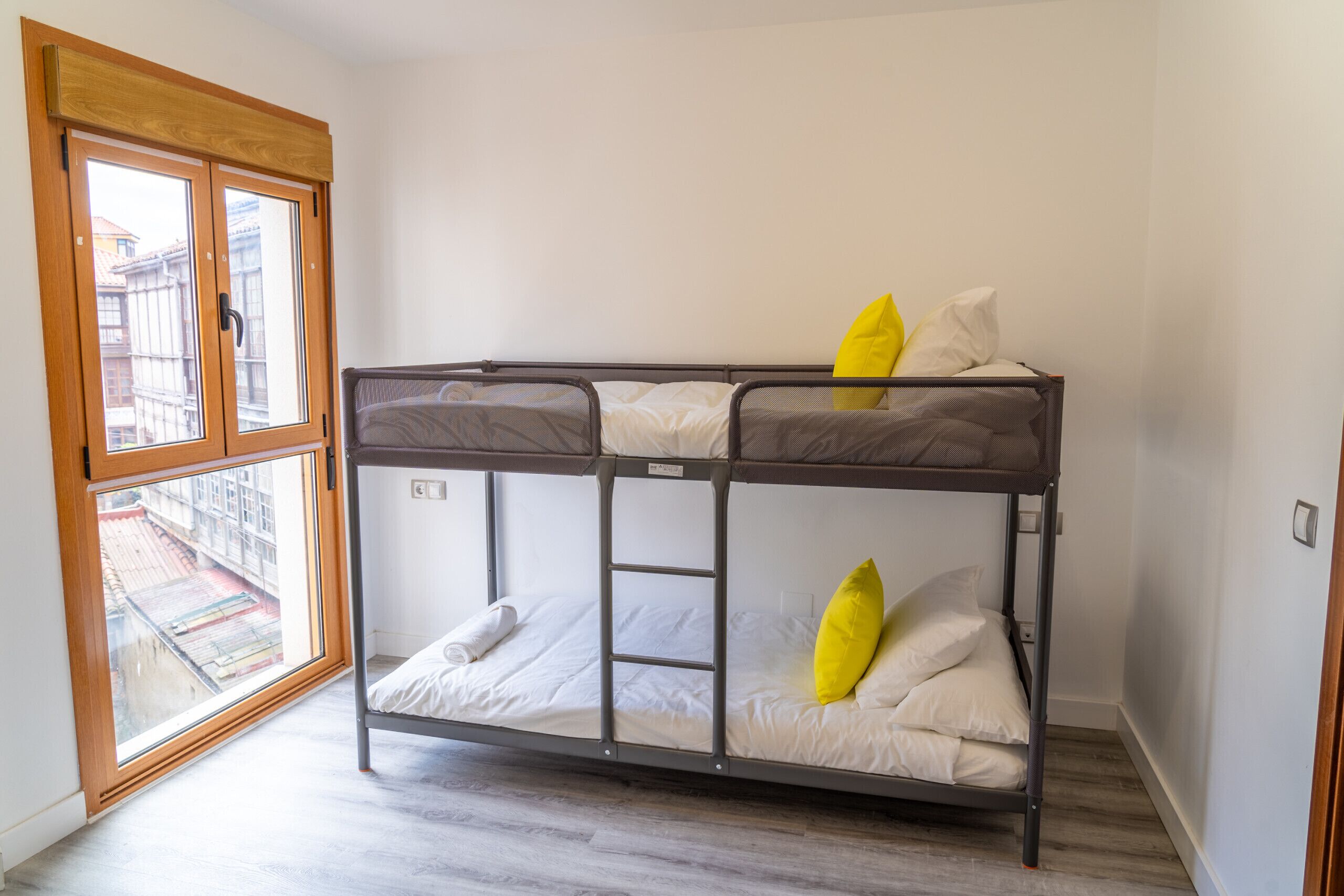 A bunk bed with a ladder, white bedding, and a yellow pillow.