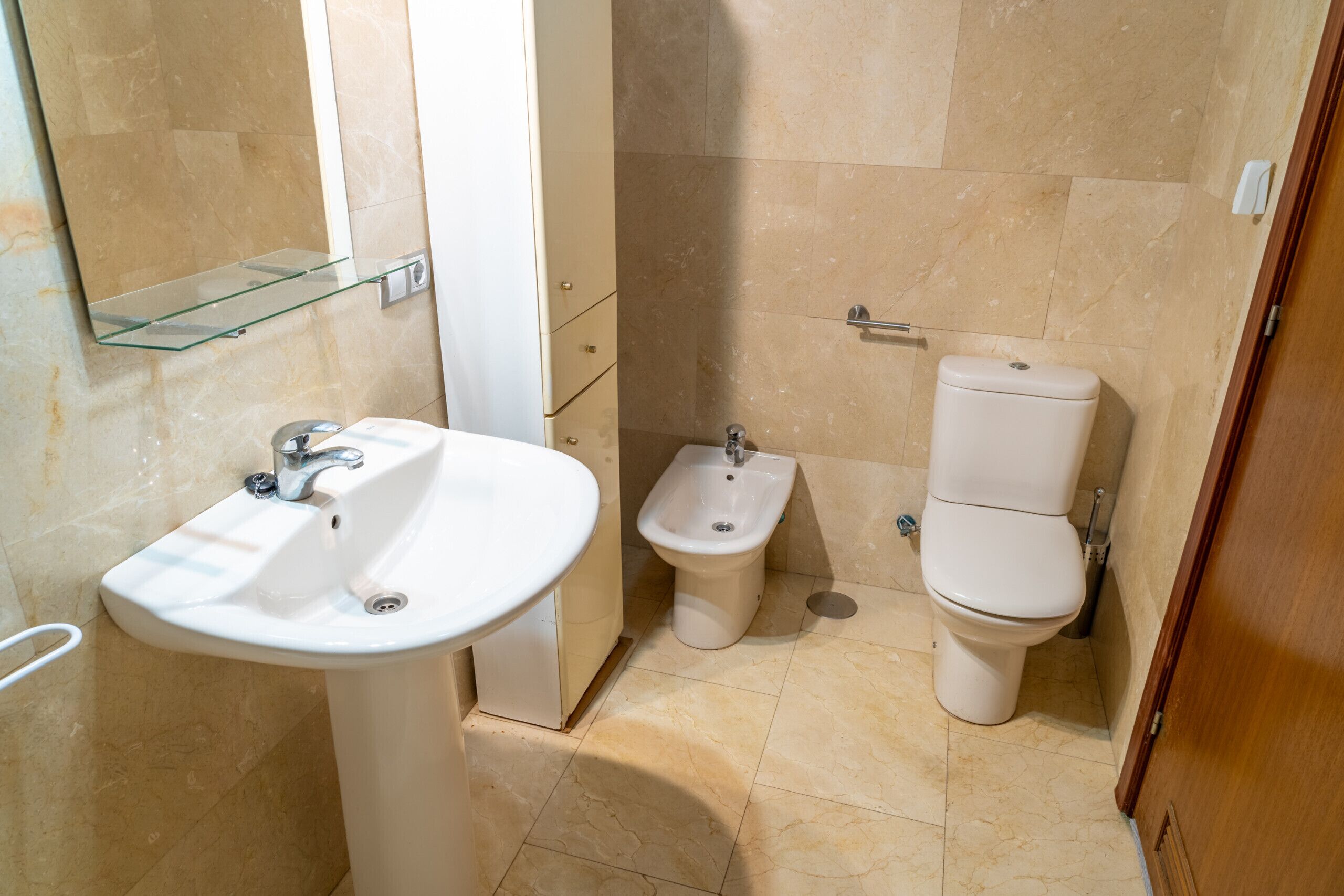 A bathroom with a white sink, bidet, and toilet.