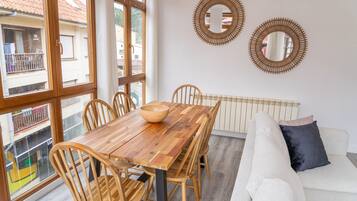 A dining area with a wooden table and chairs, a white sofa, and two wall mirrors.