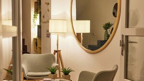 A modern hotel room with a round mirror, two armchairs, a small table, and a lamp. - Villa Vera (Salerno)