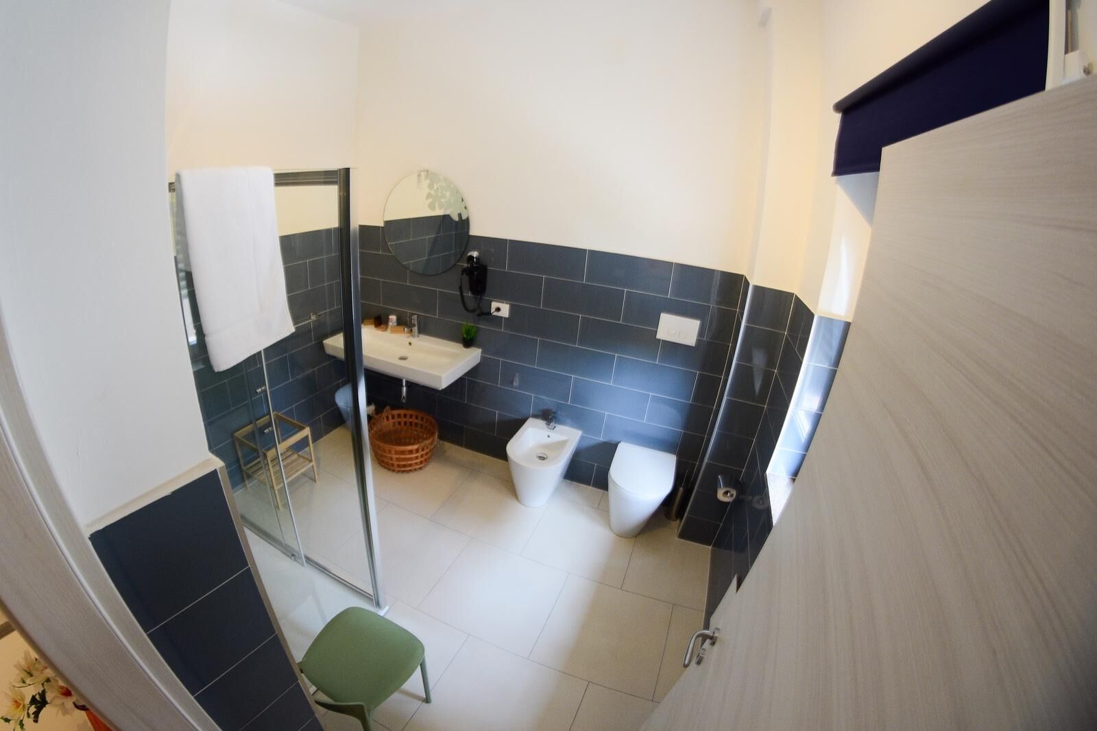 A bathroom with a white sink, a toilet, and a green chair.