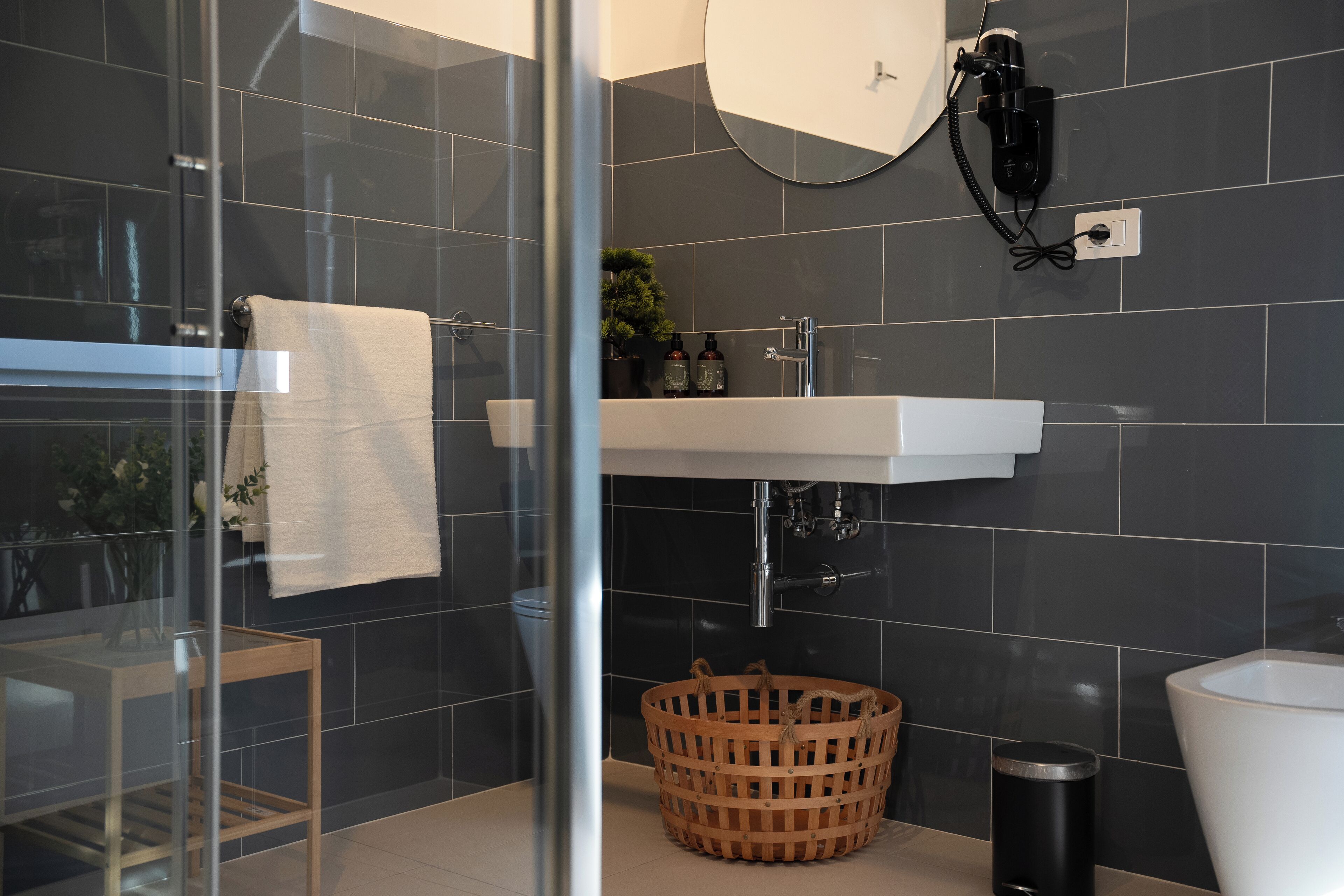 A modern bathroom with a glass shower enclosure, a white sink, and a large mirror above.