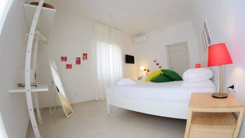 Une chambre d’hôtel moderne avec un lit aux courbes élégantes, une literie blanche, une lampe rouge et une petite table d’appoint en bois.