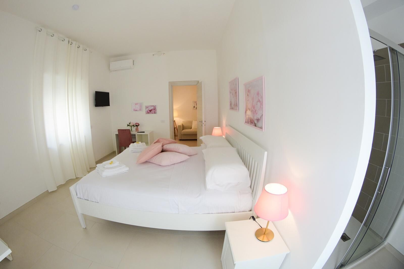 Una camera da letto moderna con un letto grande, comodini, una scrivania e un angolo doccia.