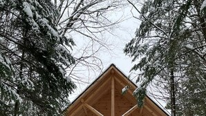 Une cabane en bois dotée d’un balcon, entourée d’arbres couverts de neige.