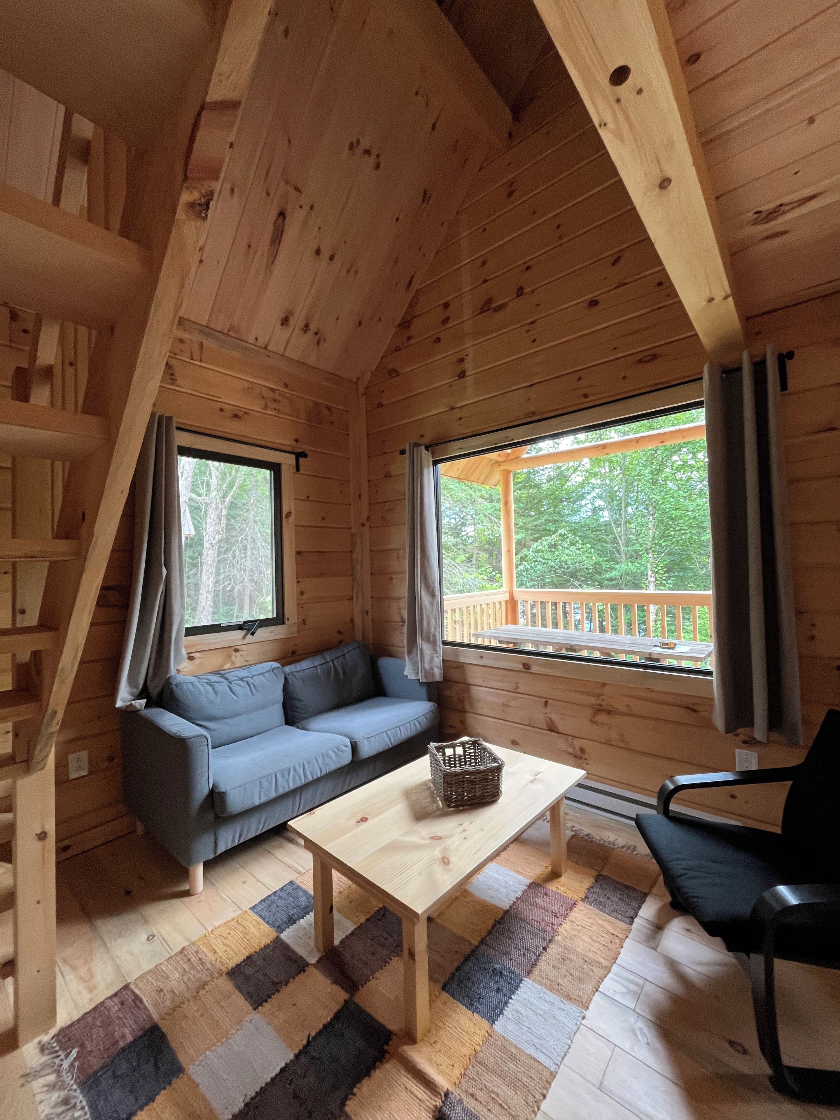 Ein Holzblockhaus-Innenraum mit einer Couch, einem Tisch und einem Stuhl.